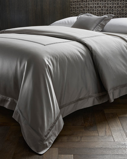 Gray sateen Nocturne sheets styled against a headboard.