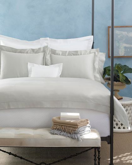 White and gray Nocturne Hemstitch bedding styled on a bed.