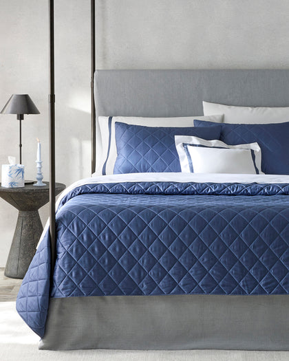 Navy diamond-quilted Nocturne Quilt bedding styled on a bed.