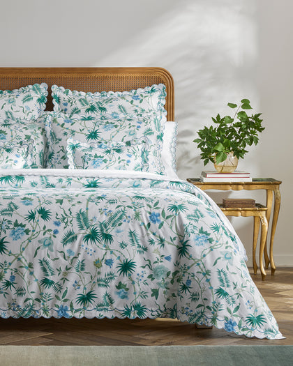 Green and blue Palmyra floral-print scalloped bedding styled against a headboard.