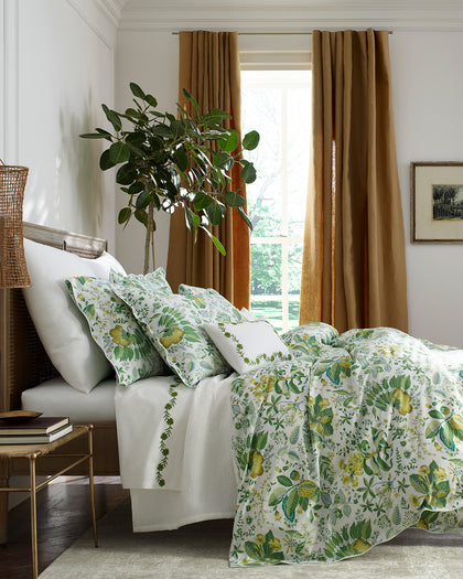 Green and yellow Pomegranate floral-print bedding styled beside a fig tree.