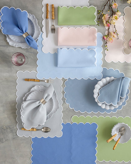 Scalloped Savannah Gardens placemats and napkins in blue, green, and pink, set with bamboo flatware from above.