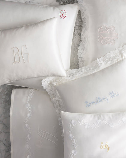White silk pillows from The Silk Collection with monogram embroidery and personalized script.