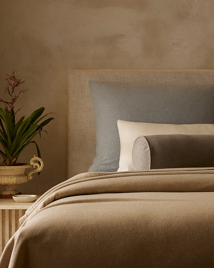 Tan Venus wool blanket layered with gray and cream wool pillows.