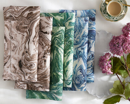 Balthazar marbled-print napkins in brown, green, and blue, folded beside a teacup and hydrangeas.