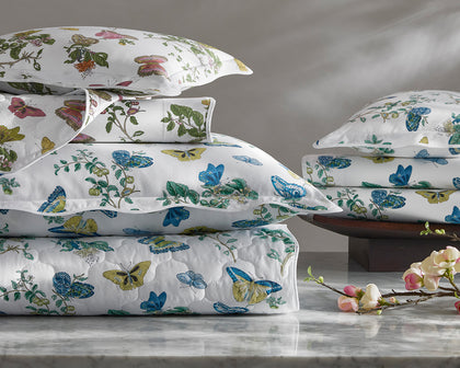 White Baudin Butterfly print bedding stacked with blue, green, and gold butterflies on a marble surface.