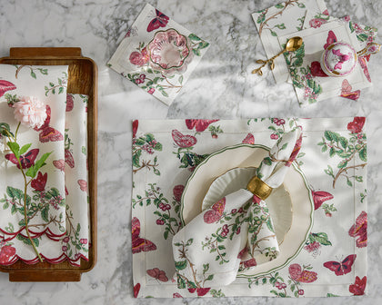 Baudin Butterfly print placemats and napkins with pink florals and butterflies, set with a scalloped plate.