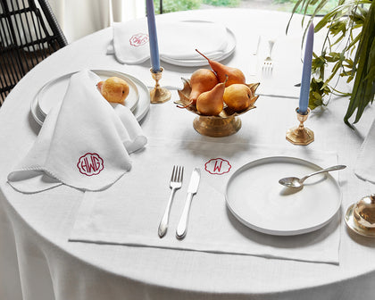 White Chamant linen tablecloth and monogrammed napkins, set with blue candlesticks and pears.