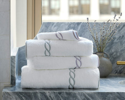 White Classic Chain towels with chain-link embroidered trim, stacked on a marble vanity.