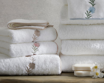 Stack of Daphne embroidered bath towels with soap and a flower
