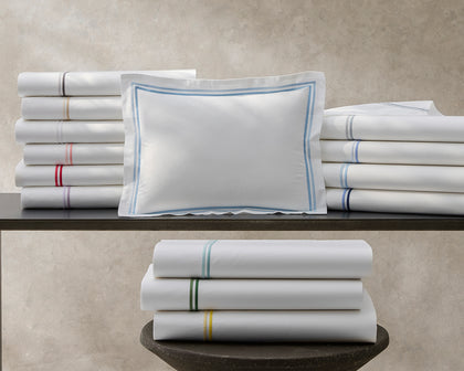White Essex bedding stacked with multicolor contrast stitching and a blue bordered pillow sham.