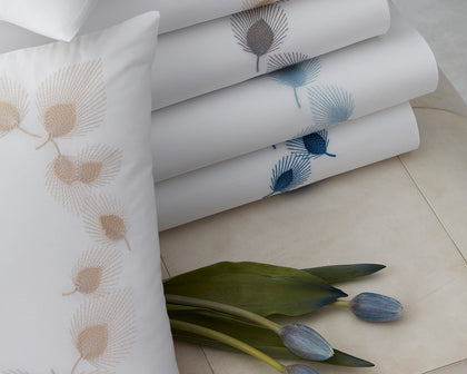 White Feather bedding embroidered with feather motifs in gold, gray, and blue.