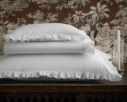 White Georgia ruffled pillow shams stacked on a dark table.