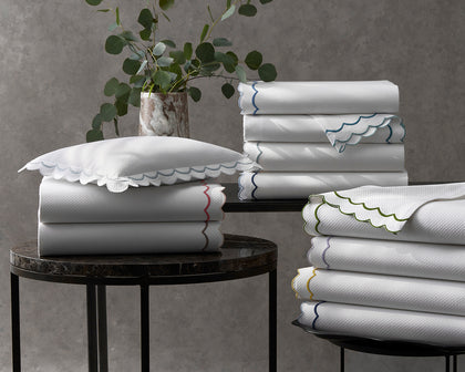 White India Pique scalloped sheets stacked with colorful trim, near a eucalyptus plant.