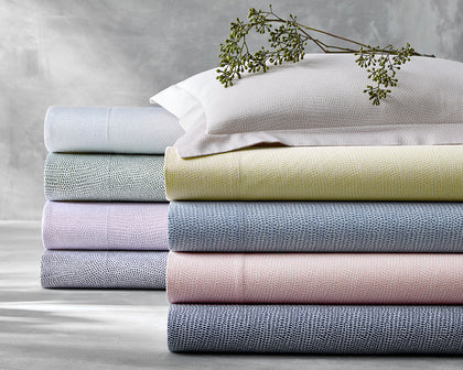 Jasper pebbled print sheets stacked in pastel colors, topped with a dried flower sprig.
