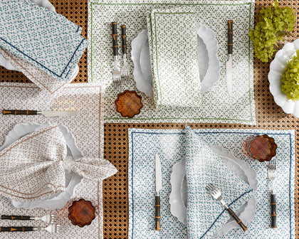 Laksha medallion print placemats and napkins in blue, green, and tan, set with scalloped plates and bamboo flatware.