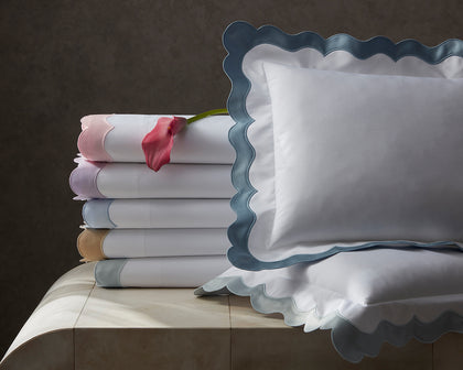 White Lorelei scalloped sheets in colorful trim, stacked with a pink calla lily.