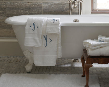 White monogrammed Lotus towels draped over a clawfoot tub.