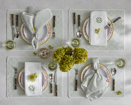 Green-striped Matteo placemats and napkins set for four with floral china and fresh hydrangeas.
