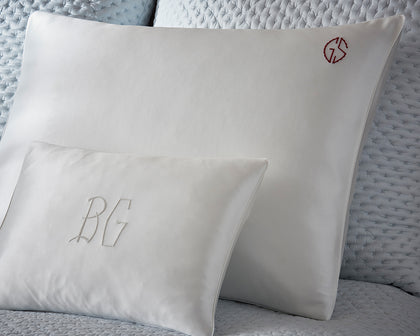 White silk monogrammed pillows from The Silk Collection styled on a quilted bed.