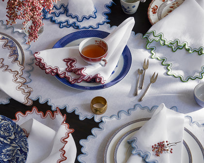 White Wave placemats and napkins with wavy trim in assorted colors, styled with blue and white china.