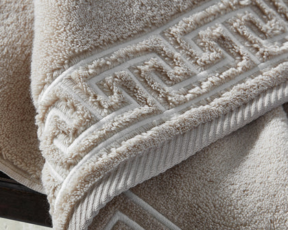 Tan Adelphi towel with textured greek-key trim, folded.
