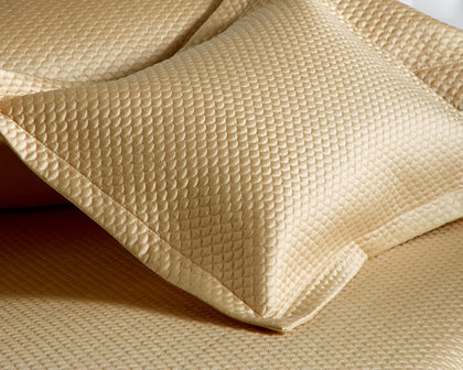 Gold Alba textured pique pillow shown in detail on matching bedding.