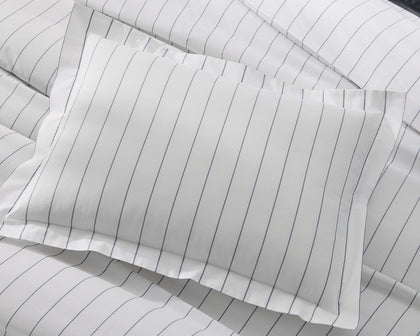 White Amalfi pinstripe pillow shown flat on matching bedding.