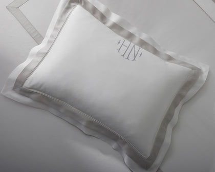 White Ambrose monogrammed pillow with satin bordered trim, shown flat.