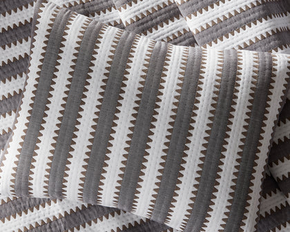 Gray Apollo Stripe Matelasse quilted pillow shown in detail on matching bedding.