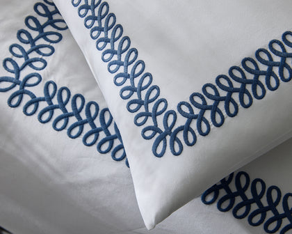 White Astor Braid pillows with navy loop-embroidered trim.