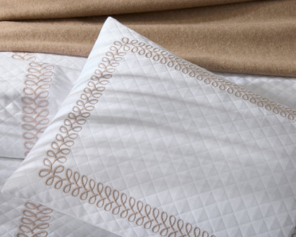 White Astor Braid quilted pillow with tan loop-embroidered trim, shown in detail.