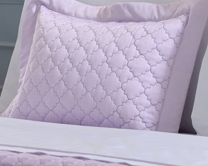 Lavender Ava quatrefoil-quilted pillow styled on a bed.