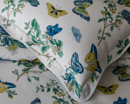 White pillow sham in the Baudin Butterfly print with blue and gold butterflies and flanged edge.