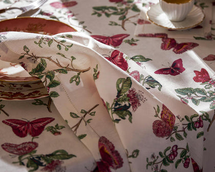 Baudin Butterfly print tablecloth with pink butterflies and florals, set with gold-rimmed china.