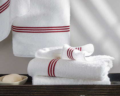 White Bel Tempo towels with red triple-stripe trim, folded beside a bar of soap.