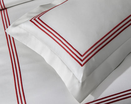 White Bel Tempo Nocturne pillow with red triple-stripe embroidered trim, shown in detail.