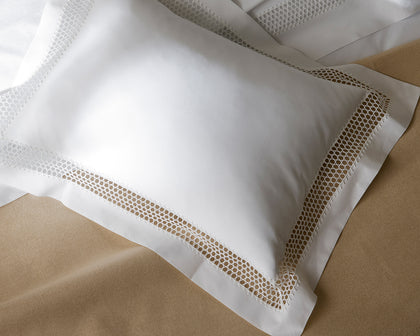 White Cecily pillow with lattice lace trim, styled on tan bedding.
