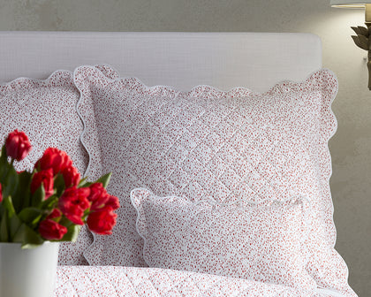 Red Celine speckled-print quilted bedding styled on a bed with red tulips.