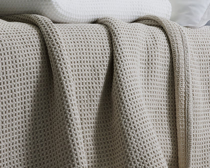 Gray waffle-weave Chatham blanket draped over a bed.