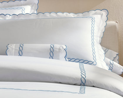 White Classic Chain Scallop bedding with blue scalloped chain-embroidered trim, styled on a bed.