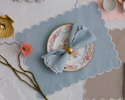 Blue Dakota scalloped placemat set with a floral plate and gold napkin ring.