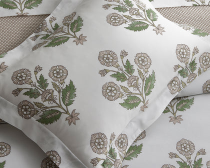 Green Dalila floral print pillow styled on a woven bed.