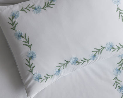 White Daphne pillow with blue floral vine embroidery.