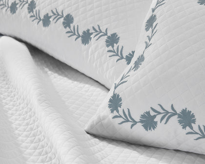 White Daphne Matelasse quilted pillow with slate blue floral vine embroidery.
