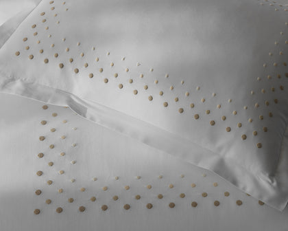 White Dorothy sheets with gold polka-dot embroidery.