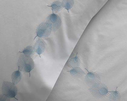 White pillow sham embroidered with a blue feather motif.