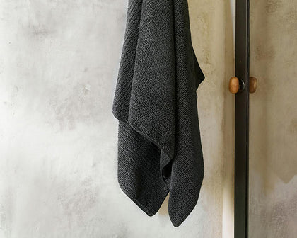 Charcoal Francisco ribbed towel hanging on a door hook.