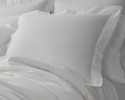 White Gatsby hemstitch pillows arranged on a bed.