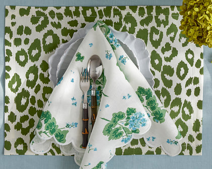Green leopard print placemat paired with a blue Geranium print napkin, set on a table.